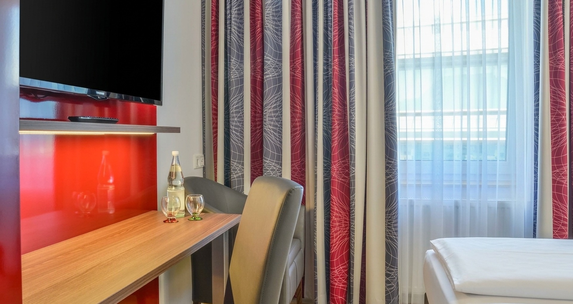 Moderne Zimmerausstattung mit Schreibtisch, Flachbild-TV und Sitzecke
